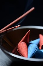 Incense cones in bowl and burning incense sticks