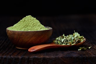 Moringa leaves in spoon and moringa powder in bowl