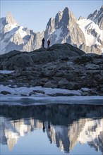 Hikers in front of a mountain panorama with water reflecting in Lac Blanc
