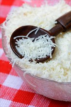 Grated Parmesan cheese in glass bowl with wooden spoon