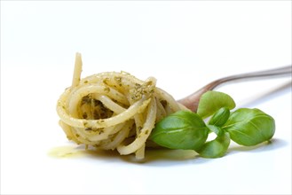 Spaghetti with pesto on fork and basil