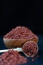 Sumac powder in wooden bowl and spoon