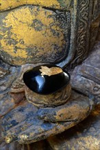 Black stone with gold plate in hand of Buddha