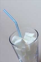 Sugar cubes in drinking glass with straw