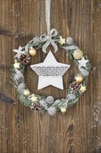 Christmas wreath on brown wooden wall with star
