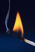 Burning match forms blue smoke