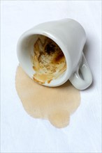 Coffee stain on tablecloth and fallen cup