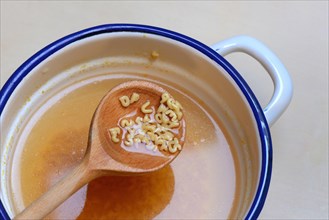 Cooking spoon with alphabet noodles and alphabet soup