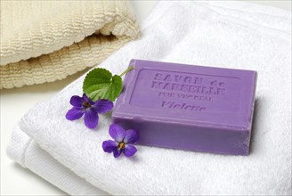 Violet soap and violet flowers on towel