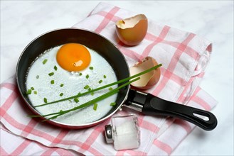 Fried egg with chives in frying pan