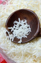 Grated Parmesan cheese in glass bowl with wooden spoon