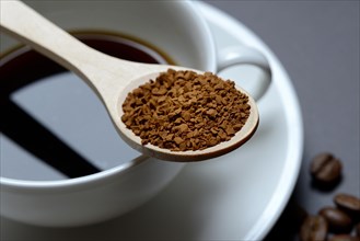 Instant coffee in spoon on coffee cup