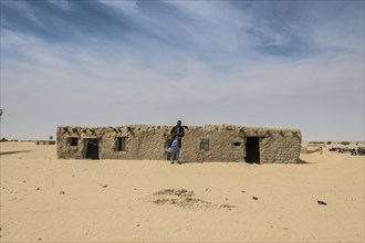 Man in front of traditional mud house