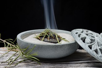 Dried rosemary leaves are burnt in a bowl with sand