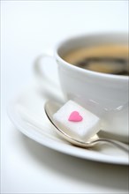Sugar cube with sugar heart and cup of coffee
