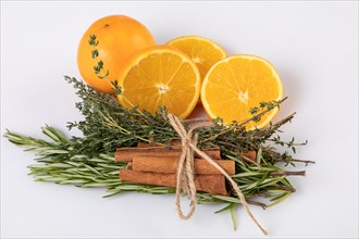 Fresh oranges with cinnamon sticks tied together with rosemary and thyme