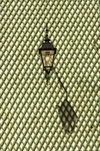 Shadow of a lantern on a green wooden lattice wall