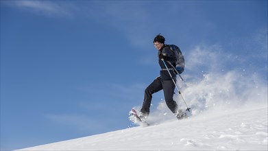 Woman with snowshoes walking through snow