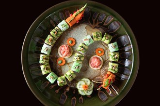 Sushi decorated in form of a dragon on round plate