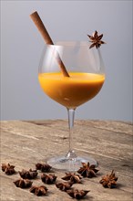 Orange fruity cocktail with cinnamon stick and star anise in a glass