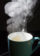 Hot water flows into a cup with a tea bag