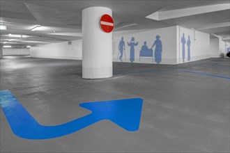 Empty underground car park and blue arrow on the floor