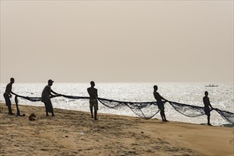 Local fishermen pulling their nets on a beach in Robertsport