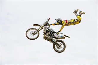 Motocross rider jumping in front of cloudy sky