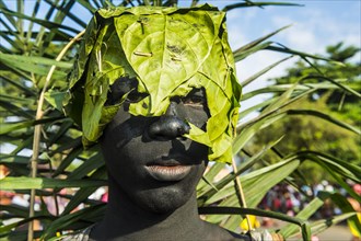 Grim looking man with a banana leaf over his head