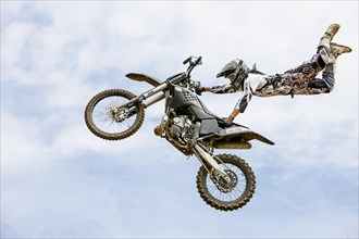 Motocross rider jumping in front of cloudy sky