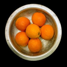 Oranges in fruit bowl on black background