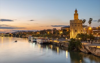 View over the river Rio Guadalquivir with Torre del Oro and promenade with excursion boats