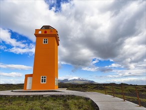 Orange lighthouse Skalasnagaviti or Svoertuloft with wooden boardwalk