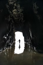 Silhouette of a person in front of cave exit in backlight