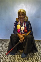 Chin Kaang hill-tribe woman with traditional facial tattoo and elaborate tribal earrings playing a flute with her nose