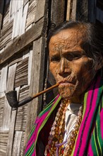 Chin woman with spiderweb tattoo smoking a pipe