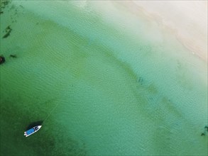 Aerial of a little boat in the clear waters anchoring on a beach on Smart island
