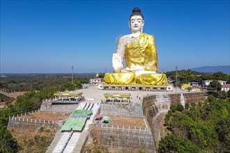 Aerial of a giant sitting buddha below the Kyaiktiyo Pagoda