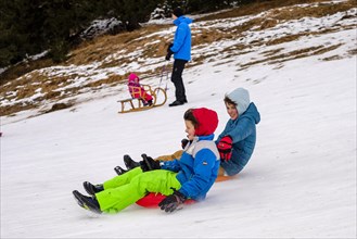 2 boys tobogganing down a snow slope with the Zipfelbob