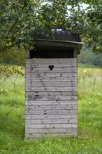 Wooden toilet house on meadow orchard