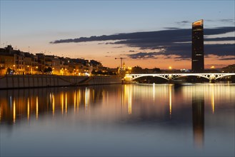 View over the river Rio Guadalquivir with illuminated bridge Puente de Triana