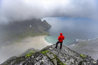 Hiker enjoys the view from Helvetestinden to the beach of Bunes