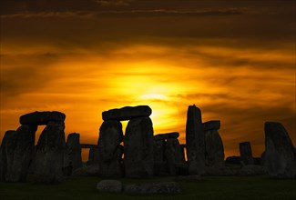 Silhouette of Stonehenge against evening sky with setting sun