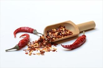 Chili flakes in wooden shovel and dried chili peppers