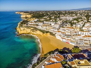 Aerial view of wide sandy beach and traditional architecture of Carvoeiro in Algarve