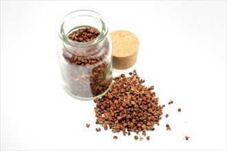 Sichuan peppercorns beside and in a 150ml glass spice jar against a white background