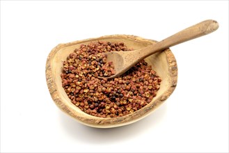 Sichuan peppercorns in a wooden rustic bowl with a wooden spoon against a white background