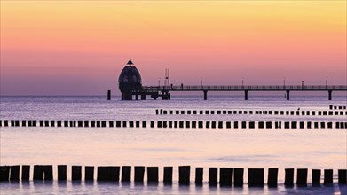 Groyne and diving bell with pier at the beach of Zingst at sunrise