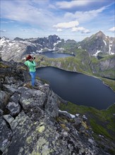 Young woman photographing mountain landscape with lake Tennesvatnet and Krokvatnet
