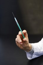 A hand holds a syringe for vaccine against COVID-19 at a vaccination center in Erding